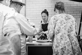 Corporate Event Photography | Melbourne Photography | Close up woman cooking and people watching black and white